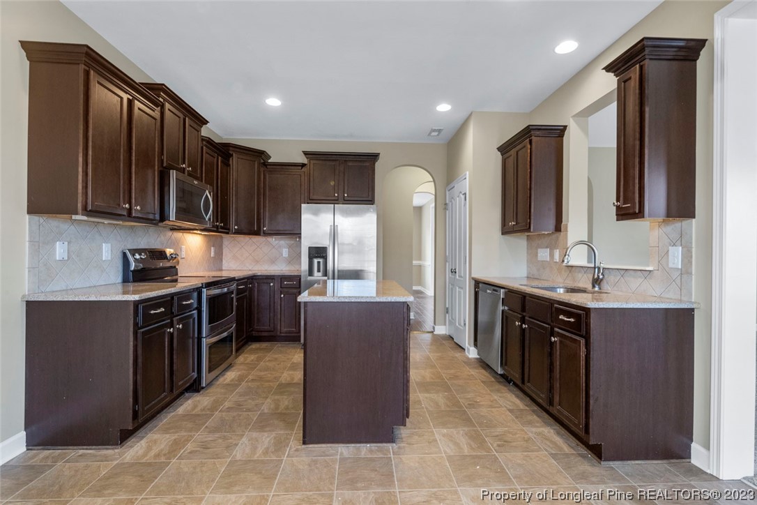 152 Copper Loop Sanford, NC 27332 - Photo 23 of 50 a large kitchen with stainless steel appliances wooden cabinets and a stove top oven