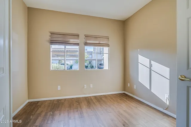 an empty room with wooden floor and windows