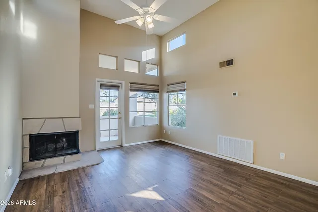 an empty room with wooden floor fireplace and windows