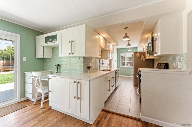 a kitchen with white cabinets and wooden floors