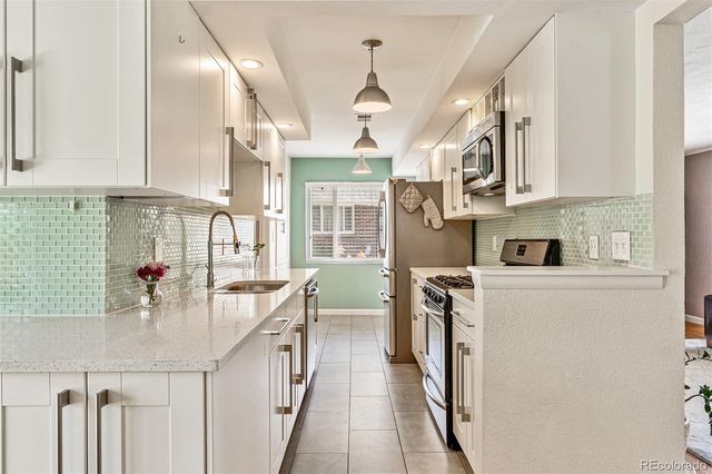a kitchen with stainless steel appliances granite countertop a sink a stove and a refrigerator