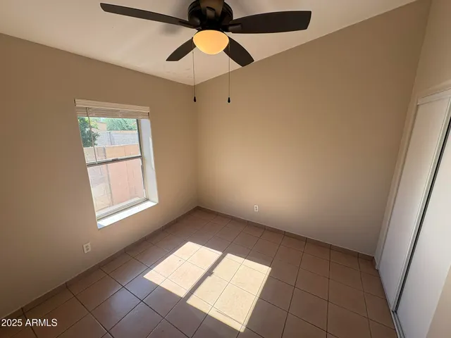 a view of an empty room with window and chandelier fan