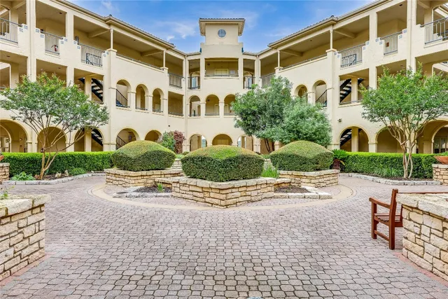 a front view of a building with garden and parking