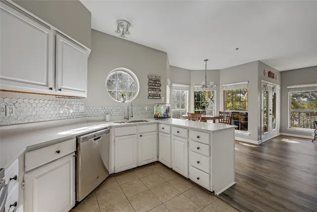 a large white kitchen with granite countertop a sink white cabinets and a dishwasher