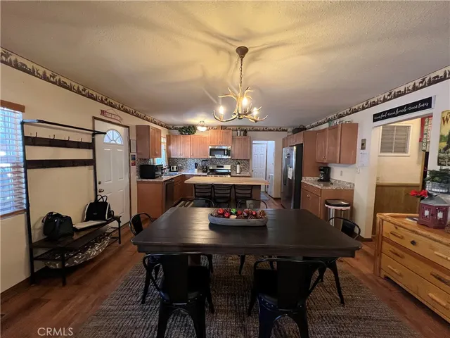 a kitchen with kitchen island granite countertop wooden cabinets a stove a sink a oven with a dining table and chairs