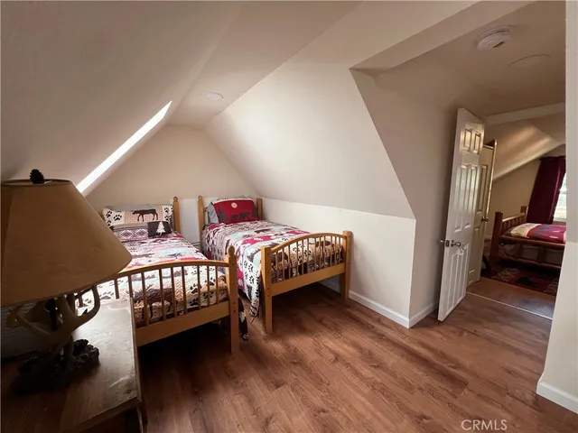 a bedroom with two beds and wooden floor