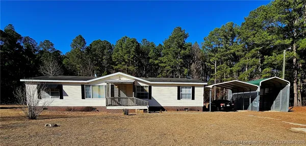 a view of house with outdoor space and trees in the background