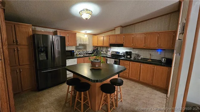 a kitchen with stainless steel appliances granite countertop a refrigerator a sink a stove a dining table and chairs