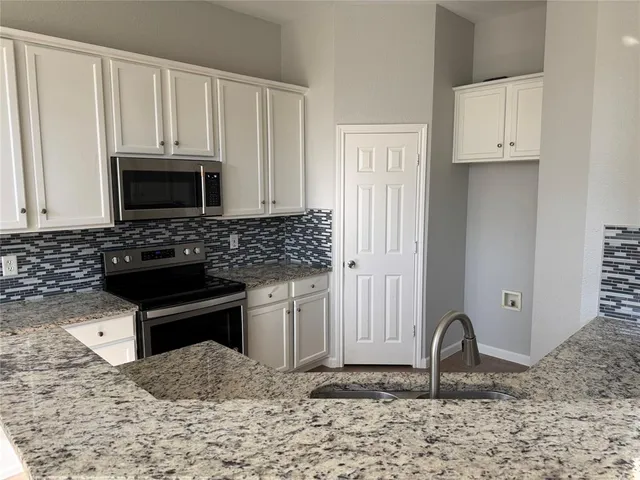 a kitchen with granite countertop a stove a sink and a microwave