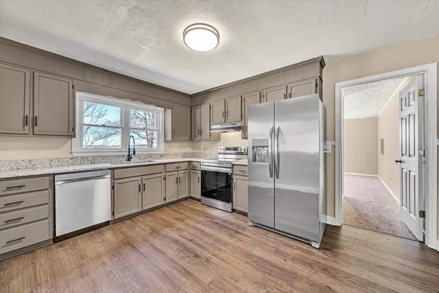 an empty room with wooden floor fan and windows