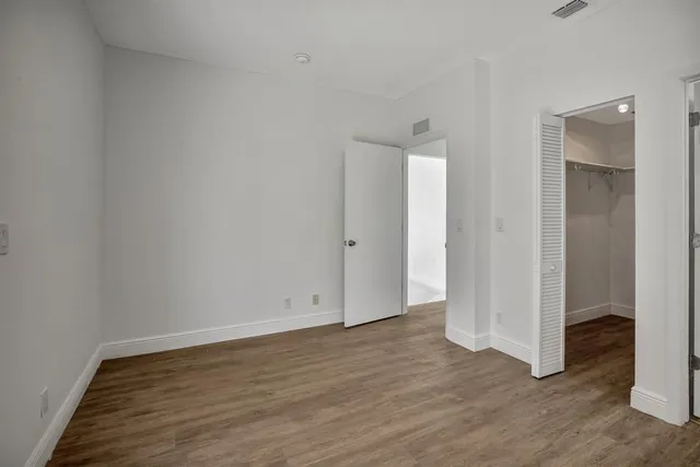 a view of an empty room with wooden floor and closet