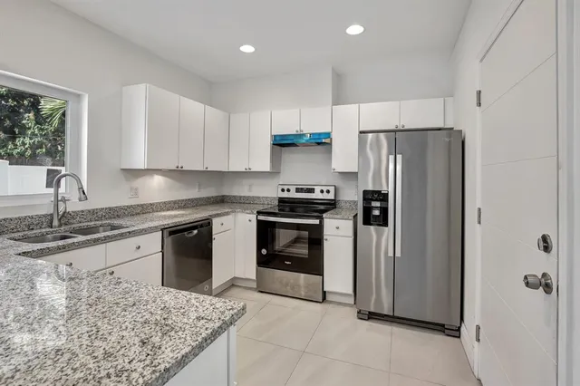 a kitchen with granite countertop a refrigerator stove and sink