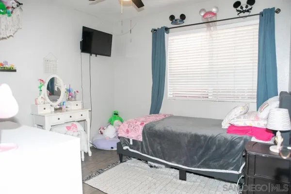 a bedroom with a bed a flat screen tv and a window