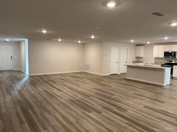 a view of a kitchen with kitchen island wooden floors granite counter tops and a view of living room