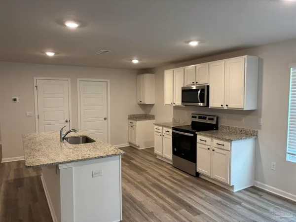 a kitchen with granite countertop white cabinets and stainless steel appliances