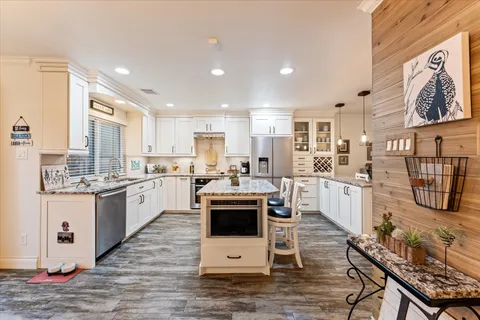 a kitchen with stainless steel appliances kitchen island granite countertop a stove and white cabinets