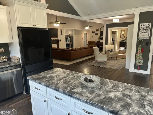 a living room with stainless steel appliances kitchen island granite countertop a refrigerator and cabinets