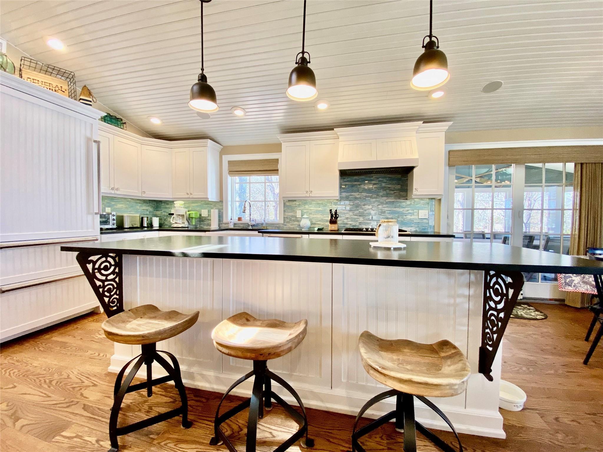 780 Minnehaha Boulevard Southold, NY 11971 - Photo 4 of 23 Kitchen featuring a breakfast bar, white cabinetry, stone countertops, and light wood-style floors