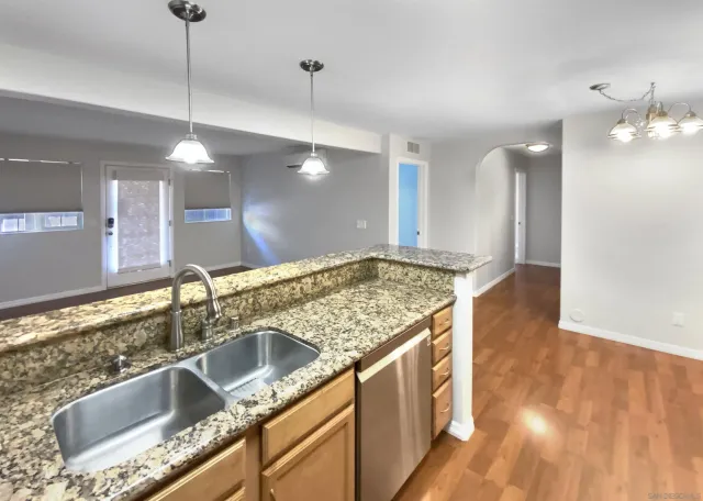 a kitchen with stainless steel appliances granite countertop a sink a counter space and wooden floor