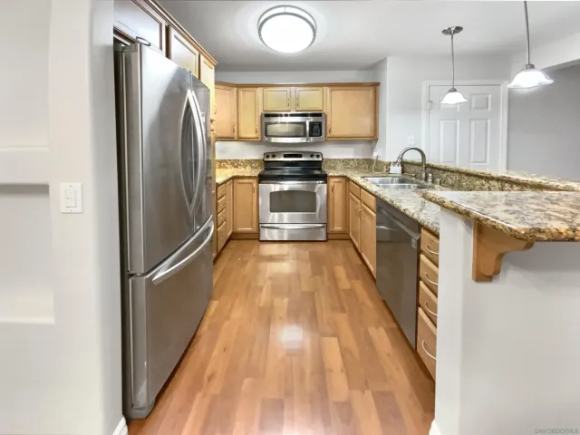 a kitchen with stainless steel appliances granite countertop a refrigerator a stove and a sink