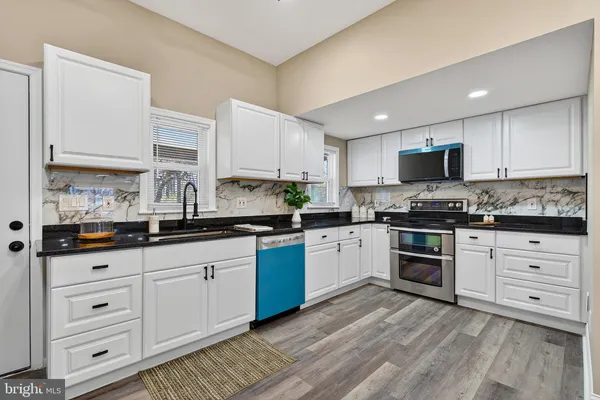 a kitchen with granite countertop white cabinets and stainless steel appliances