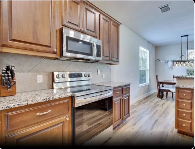 a kitchen with stainless steel appliances granite countertop a stove microwave and cabinets