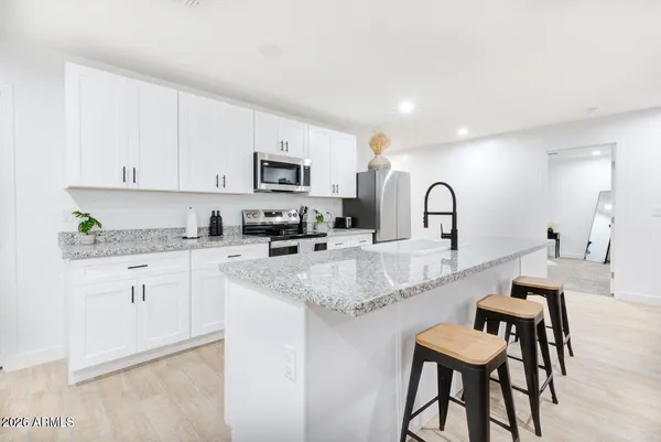 a kitchen with granite countertop white cabinets and chairs