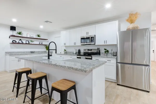 a kitchen with stainless steel appliances granite countertop a sink a stove a refrigerator cabinets and chairs