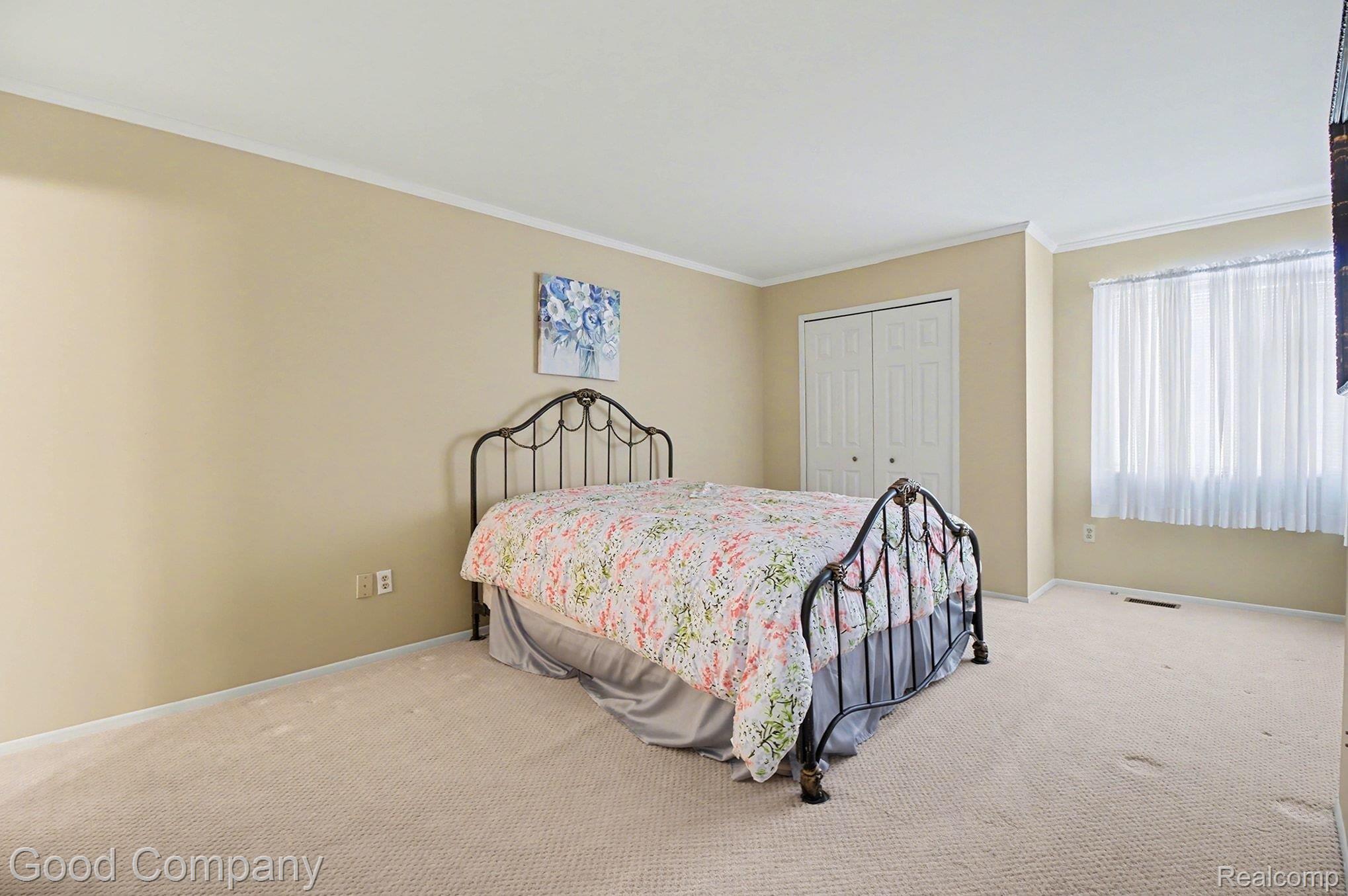 Carpeted bedroom with crown molding and a closet