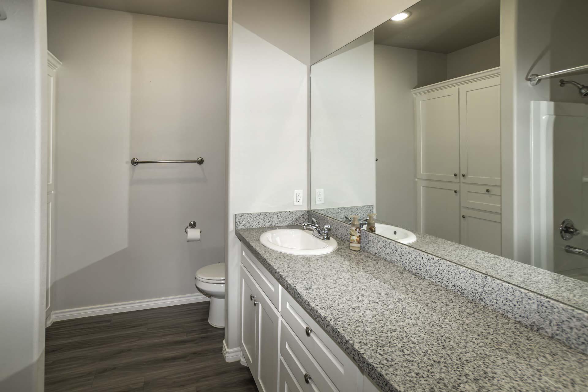 7012 12th Street Lubbock, TX 79416 - Photo 11 of 15 a bathroom with a granite countertop sink toilet and shower