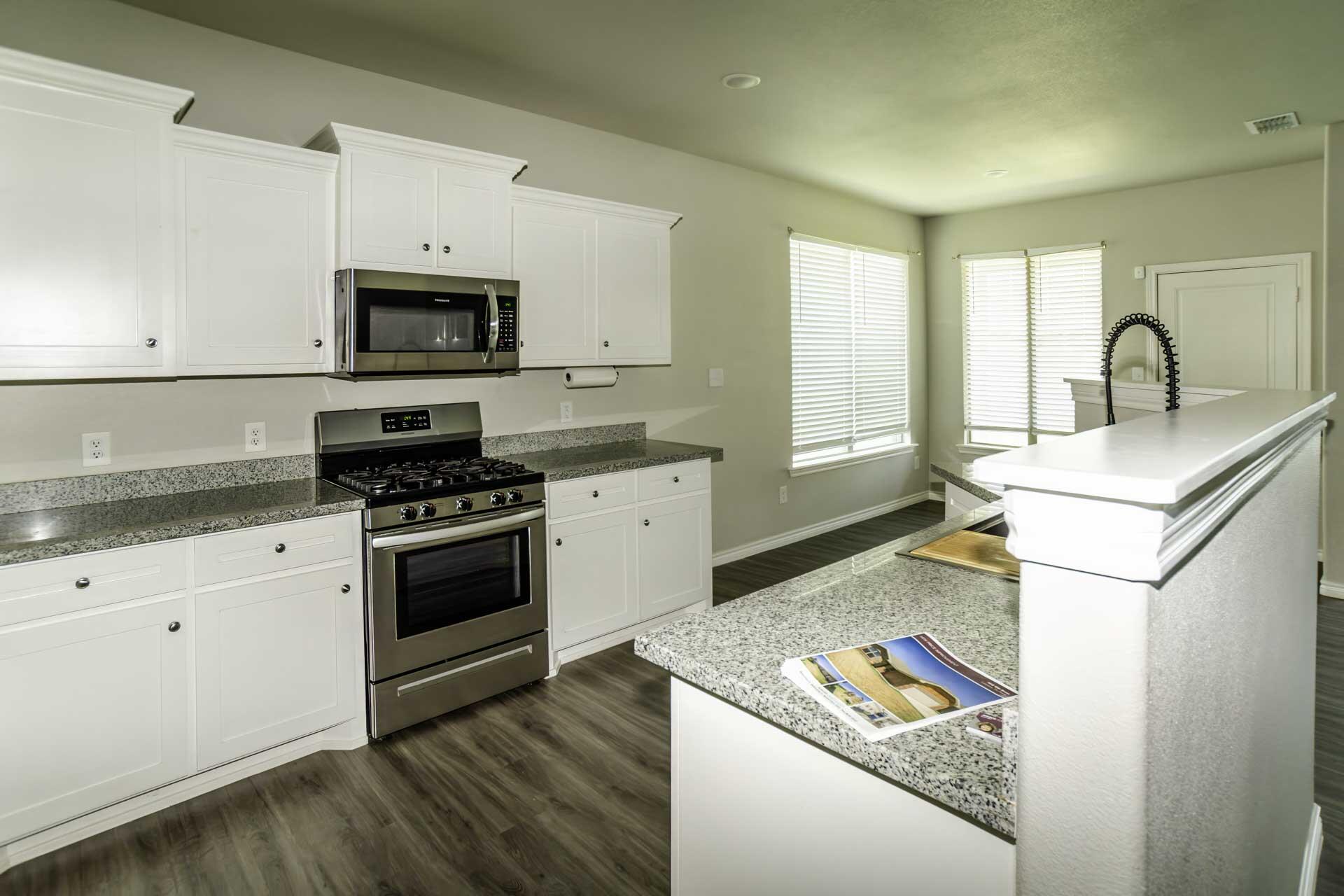 7012 12th Street Lubbock, TX 79416 - Photo 8 of 15 a kitchen with stainless steel appliances granite countertop a stove a sink and a microwave
