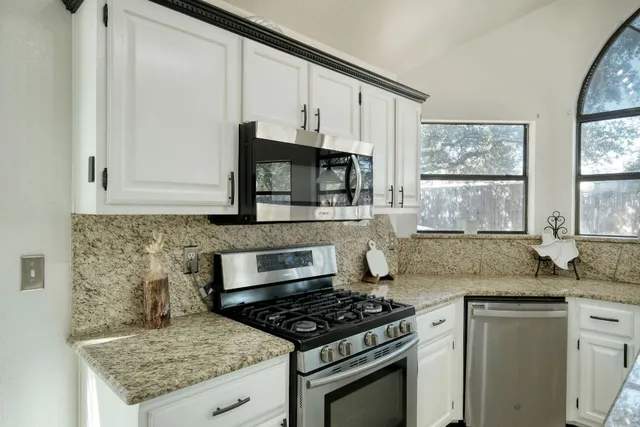 a kitchen with granite countertop a sink stove and cabinets