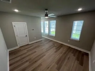 an empty room with wooden floor and windows