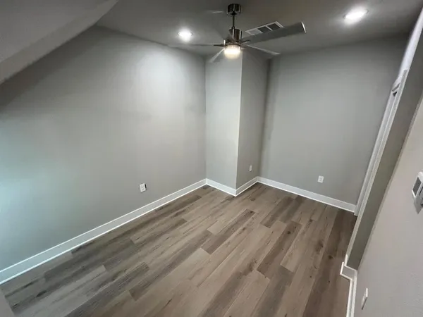 an empty room with wooden floor ceiling fan and window