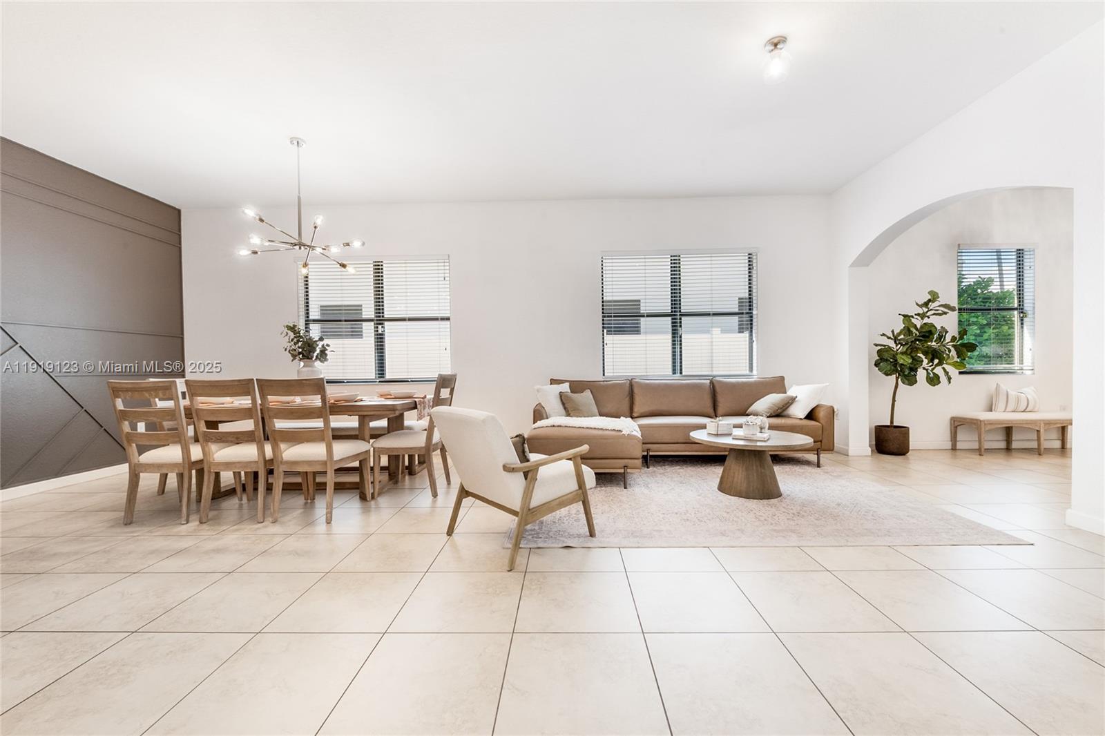 3550 West 86th Terrace, Unit 3550 Hialeah, FL 33018 - Photo 5 of 17 a living room with furniture a chandelier and a dining table