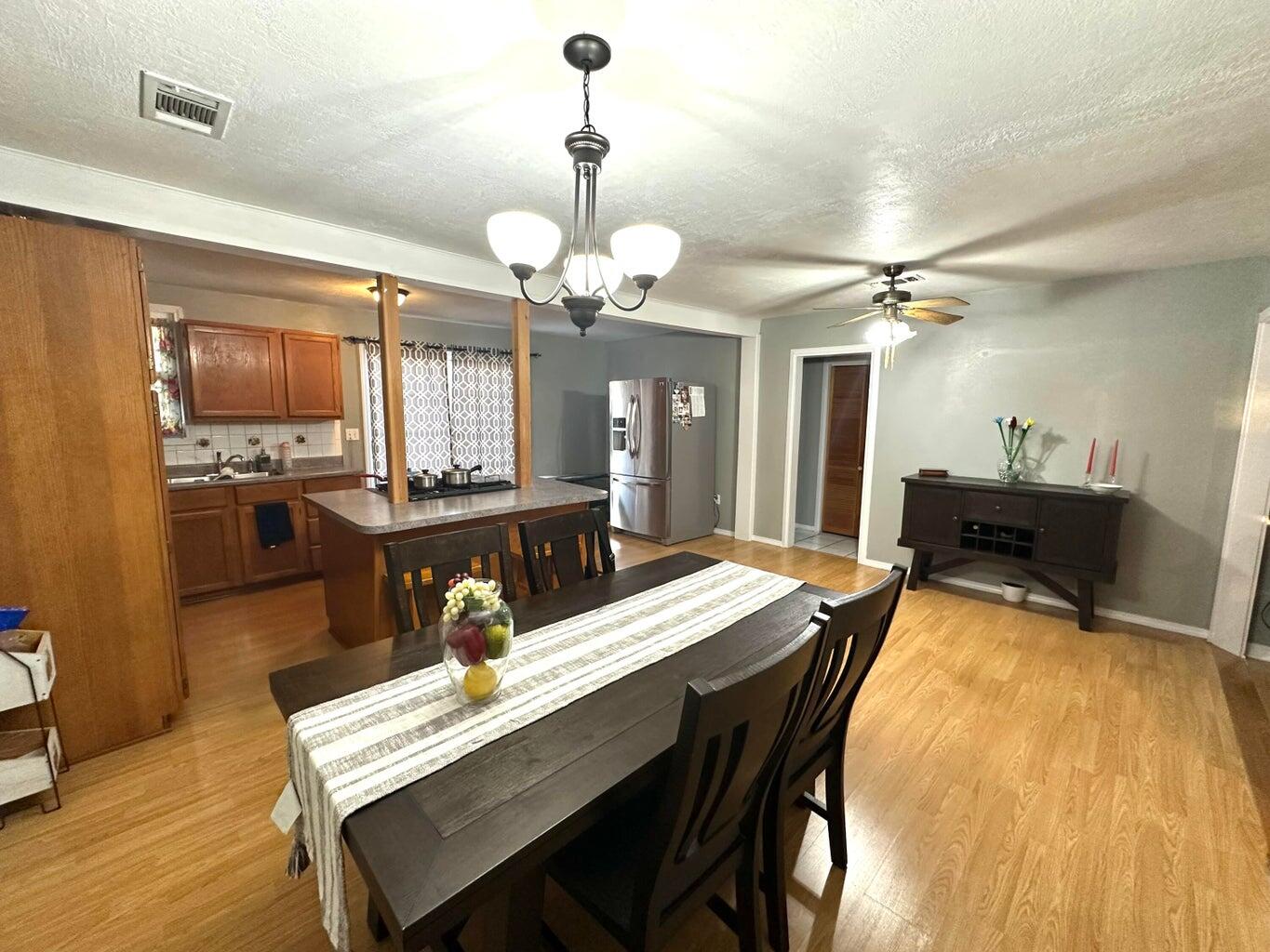 401 Xenia Street Plainview, TX 79072 - Photo 7 of 20 a dining room with wooden floor a chandelier a wooden table and chairs