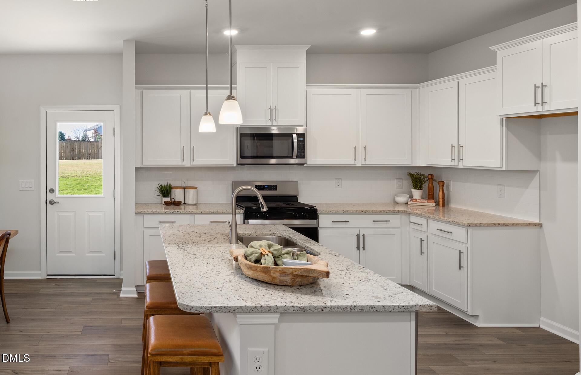 2814 Rodeo Court Fuquay-Varina, NC 27526 - Photo 7 of 31 a kitchen with kitchen island granite countertop wooden cabinets a stove a sink and a center island