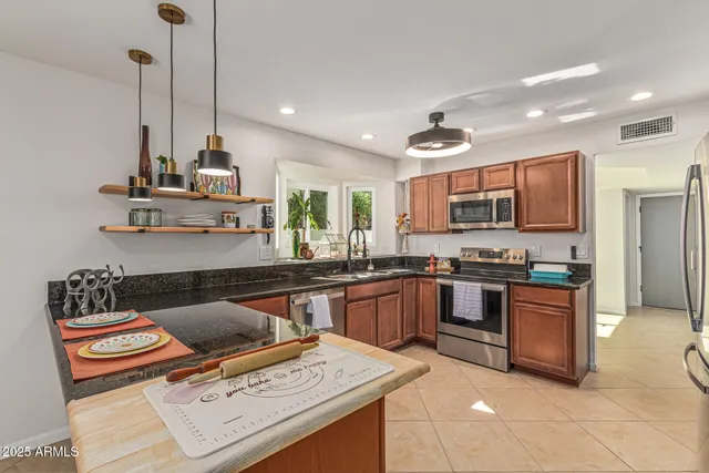 a kitchen with stainless steel appliances kitchen island granite countertop a sink a stove and a wooden floor