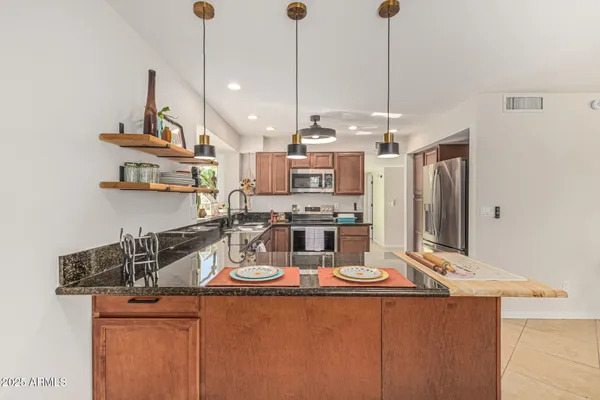 a kitchen with stainless steel appliances granite countertop a sink a stove and a refrigerator