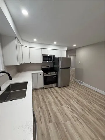 a kitchen with stainless steel appliances kitchen island granite countertop a refrigerator and a stove top oven