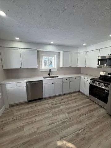 a large kitchen with stainless steel appliances granite countertop a stove a sink dishwasher and a refrigerator