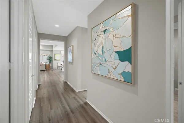 a view of a hallway with wooden floor and a bathroom