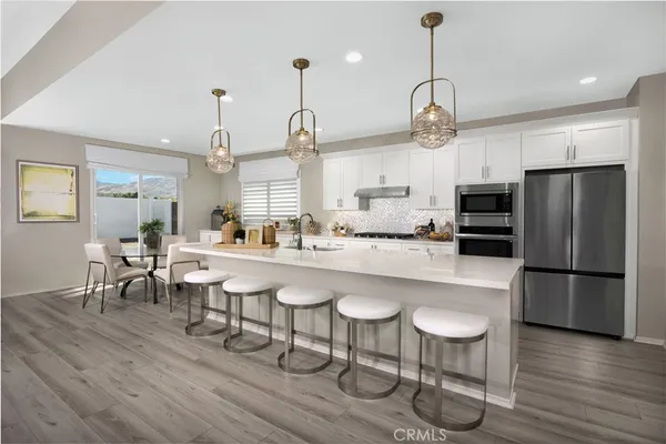 a kitchen with stainless steel appliances a dining table chairs refrigerator and sink