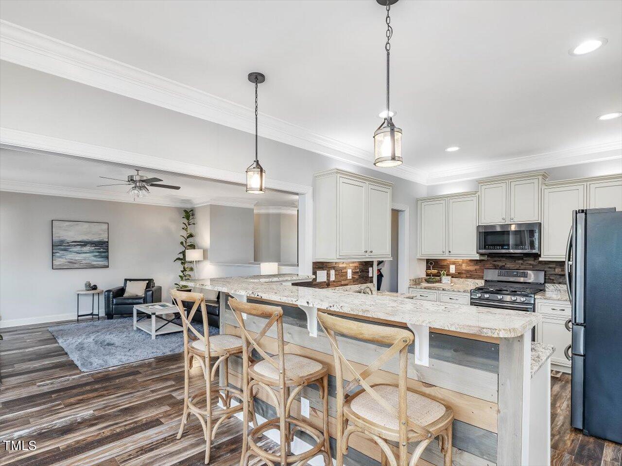 406 Gum Springs Church Road Moncure, NC 27559 - Photo 28 of 100 a kitchen with stainless steel appliances kitchen island granite countertop a stove a refrigerator a sink a dining table with chairs and white cabinets