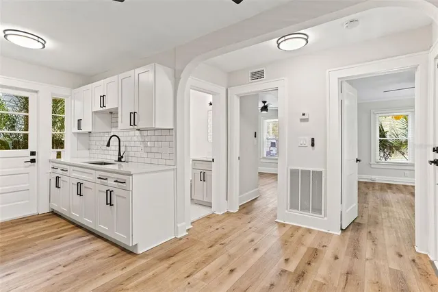 a kitchen with white cabinets and wooden floor