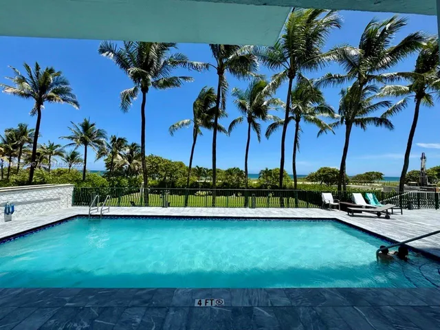 a view of a swimming pool with a bench and lawn chairs