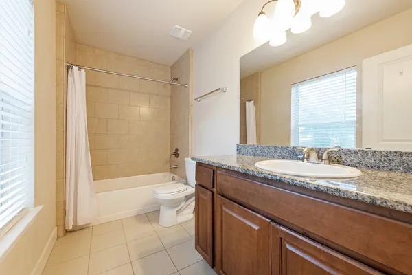 a bathroom with a granite countertop sink a toilet a mirror and bathtub