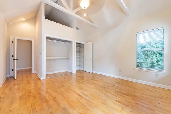 a view of an empty room with wooden floor and a window