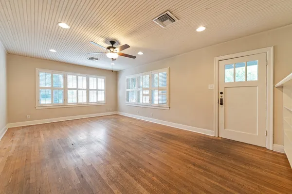 a view of an empty room with wooden floor and a window