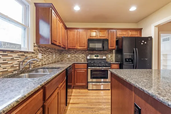 a kitchen with stainless steel appliances granite countertop a sink stove and refrigerator